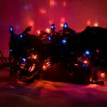 Tangled string lights with blue and red LEDs glowing in a dark setting, laid on a surface as decorative lighting practicing festive ambiance.
