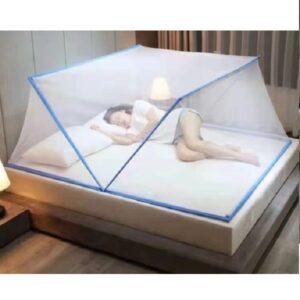 Person sleeping on a bed under a white mesh mosquito net with blue trim in a hotel room.