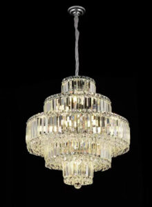 Crystal chandelier with multiple tiers suspended by a twisted cord against a black background, illuminated softly by internal lights.